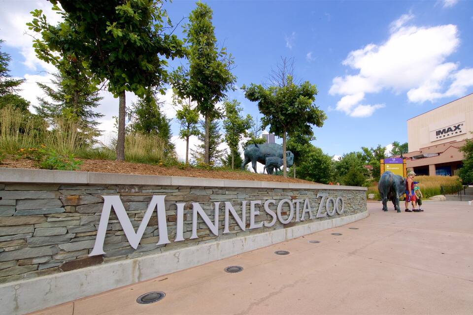 L’entrée du zoo du Minnesota, avec un mur de pierre, des arbres et un cinéma IMAX en arrière-plan.