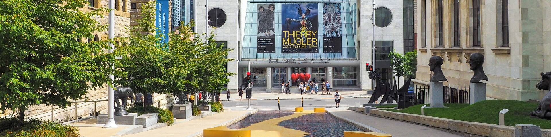 Una plaza con un colorido diseño de mosaicos, un edificio grande con un cartel de teatro y arquitectura clásica.