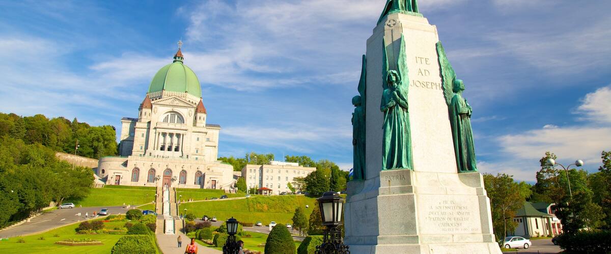 A statue of a religious figure with inscriptions, a large green-domed building, and a well-maintained park with pathways.