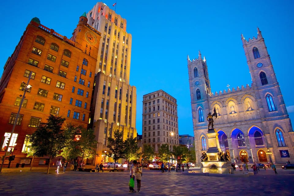 A city square with historic buildings and a prominent church tower at dusk.