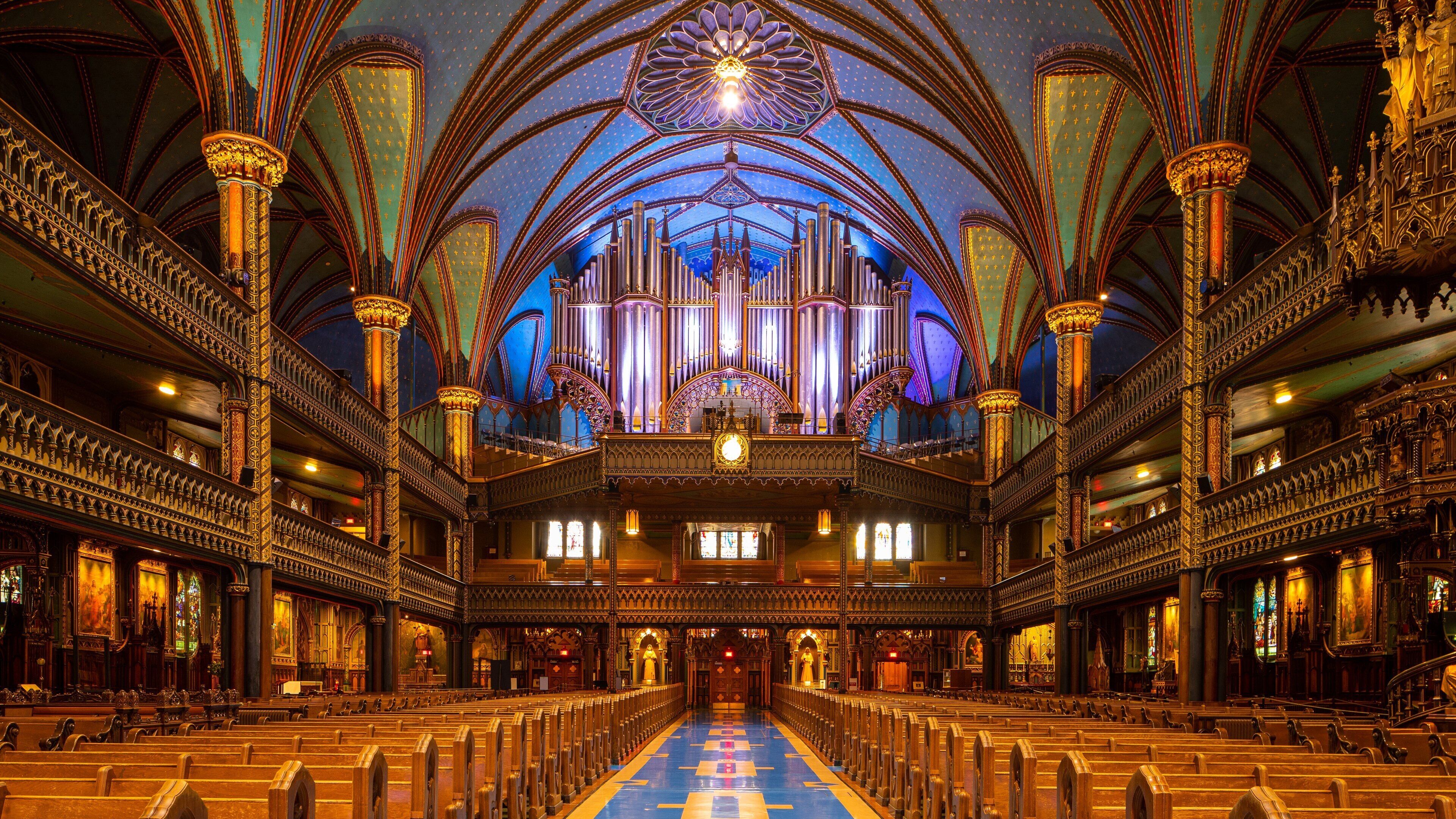 An ornate church interior with a large pipe organ, high vaulted ceilings, and rows of pews.