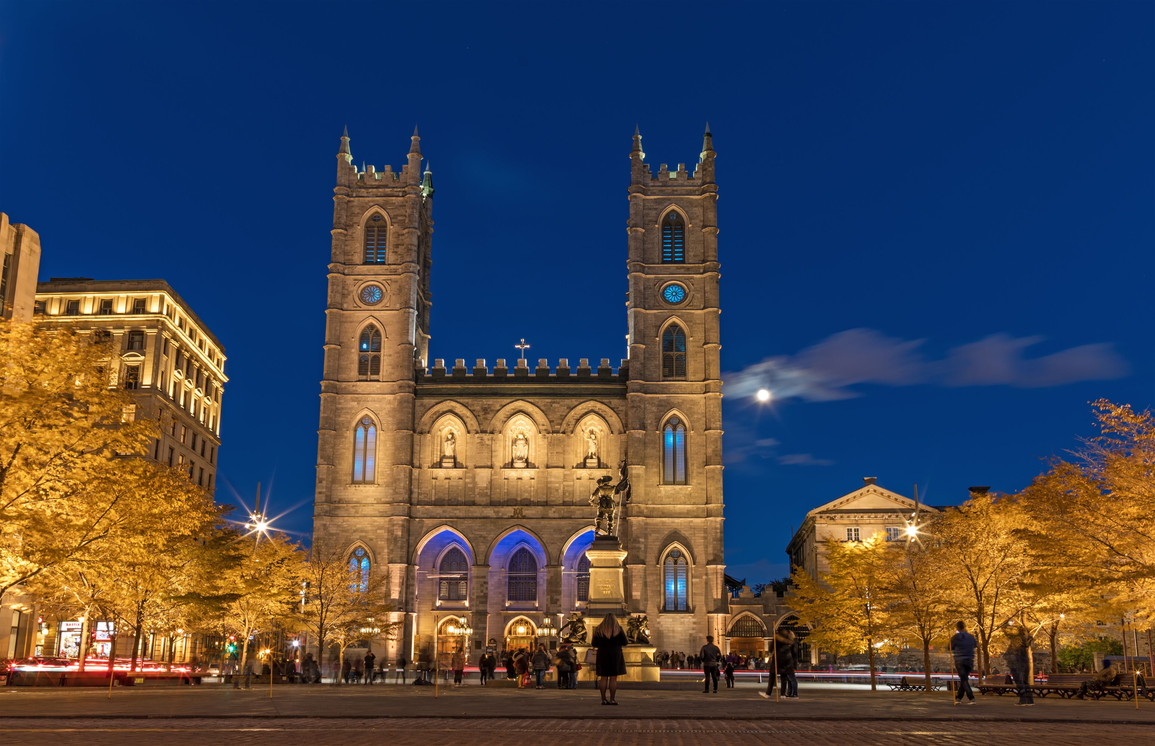 Montreal, Canada, October 20, 2018. Notre Dame Basilica from Montreal and Maisonneuve Monument illuminated at night time, during autumn season.  First neo-gothic church in Canada.
