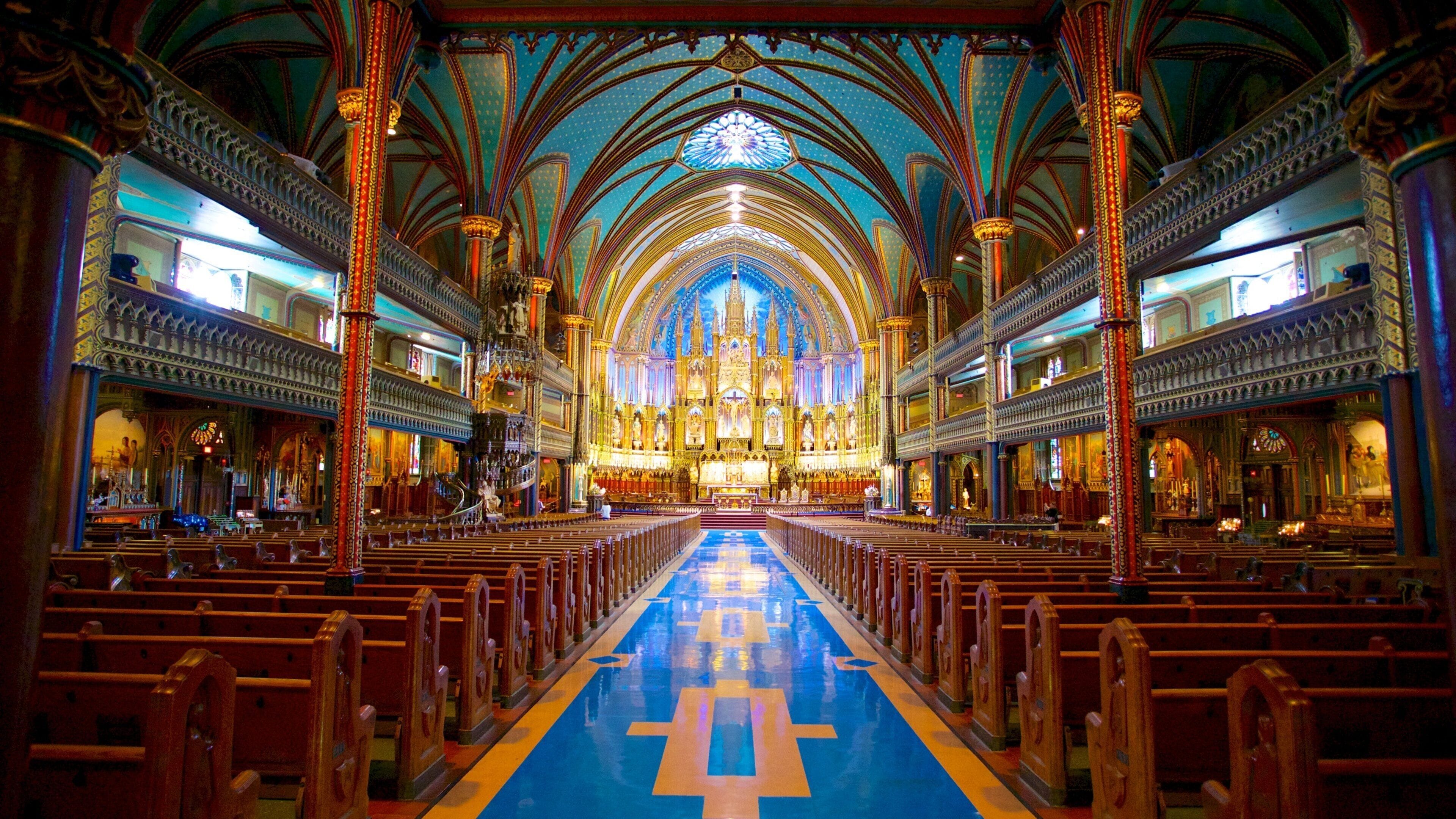 Interior de una catedral con un pasillo central, columnas ornamentales y un vitral.