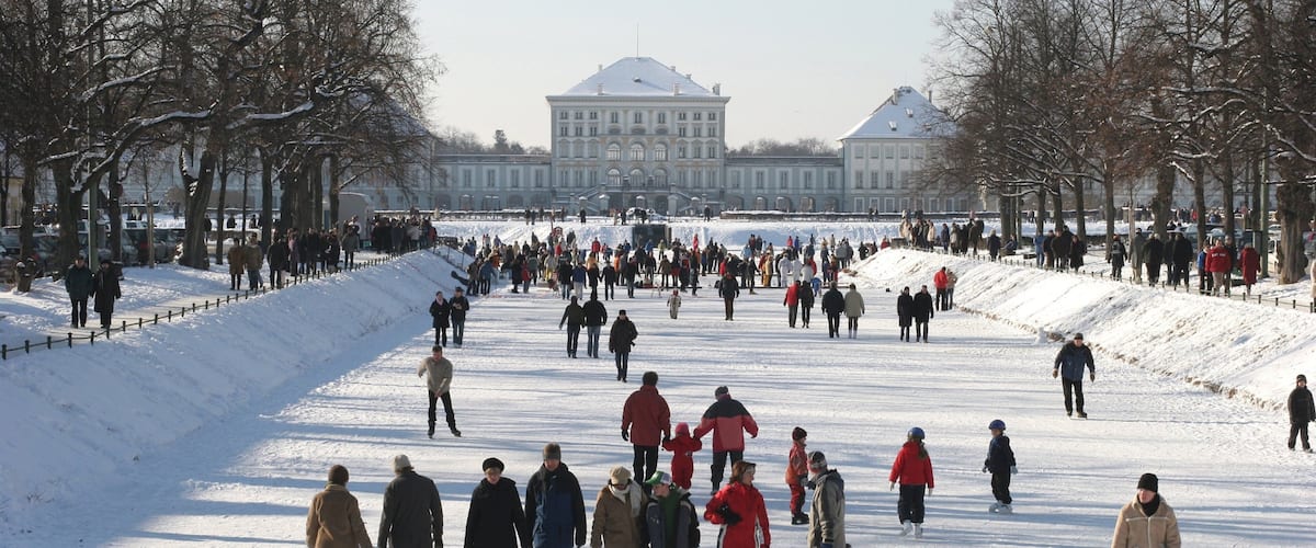 Nymphenburg Palace featuring a park and snow as well as a large group of people