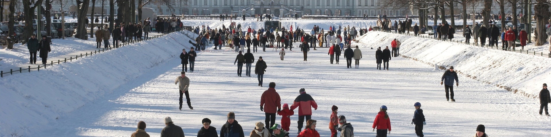 Nymphenburg Palace featuring a park and snow as well as a large group of people