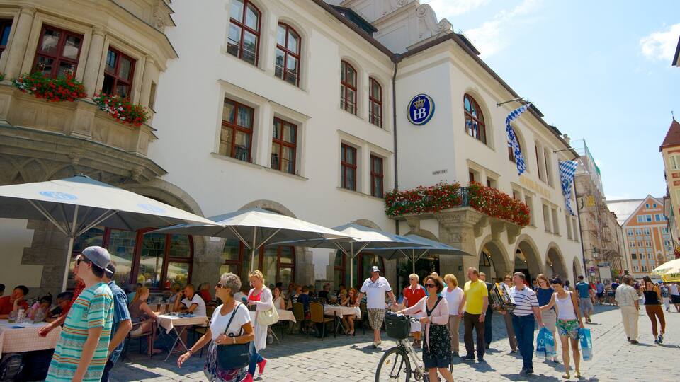 Una animada calle europea con cafés al aire libre, edificios históricos y peatones.