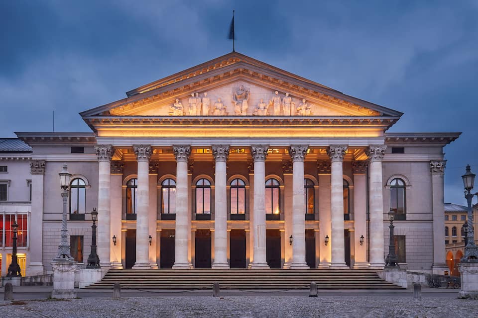 Un edificio neoclassico con un timpano centrale, ampie colonne e una bandiera sulla sommità.