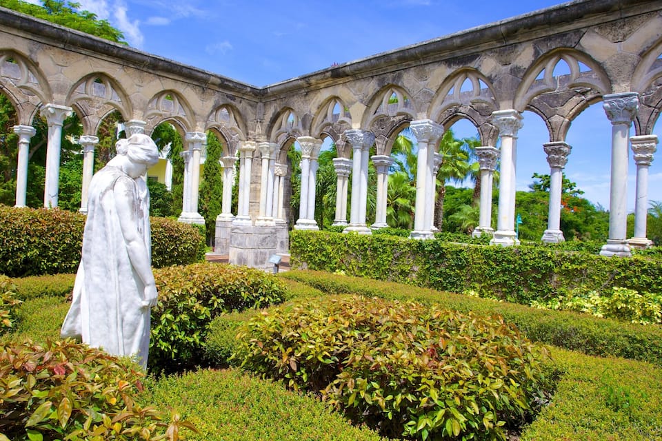 Eine Statue in einem Garten mit einem steinernen Bogen im Hintergrund.