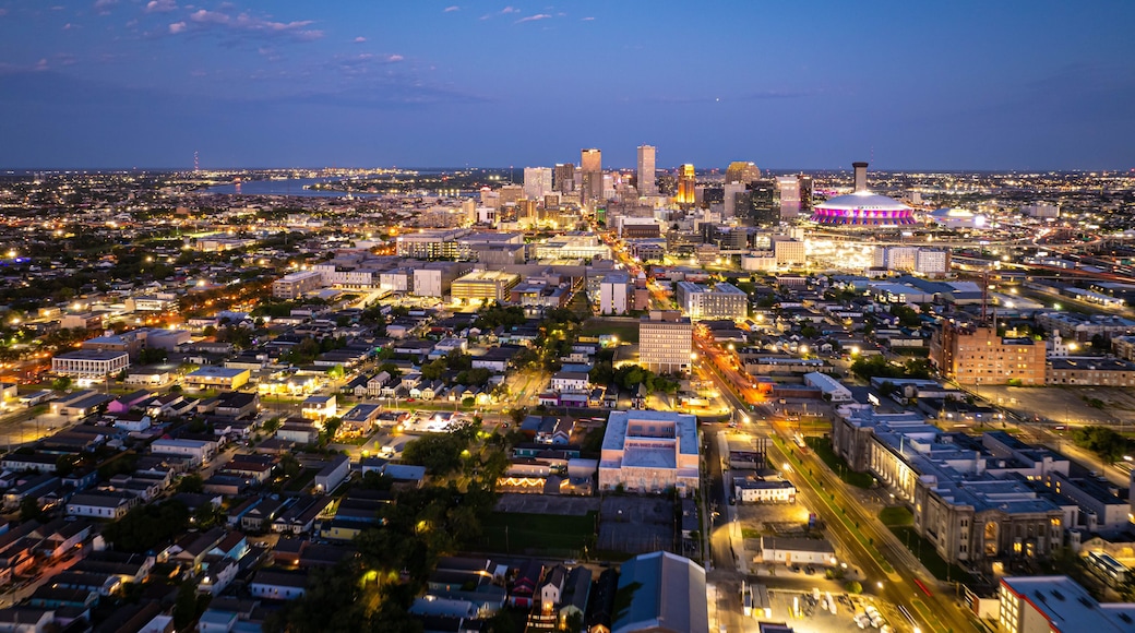 Aerial view of New Orleans skyline illuminating at dusk, showcasing vibrant city lights, prominent buildings, and the iconic Caesar Superdome under a beautiful twilight sky