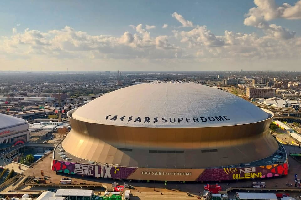 The Caesars Superdome with a large, rounded roof and the 'Super Bowl LIX' sign.