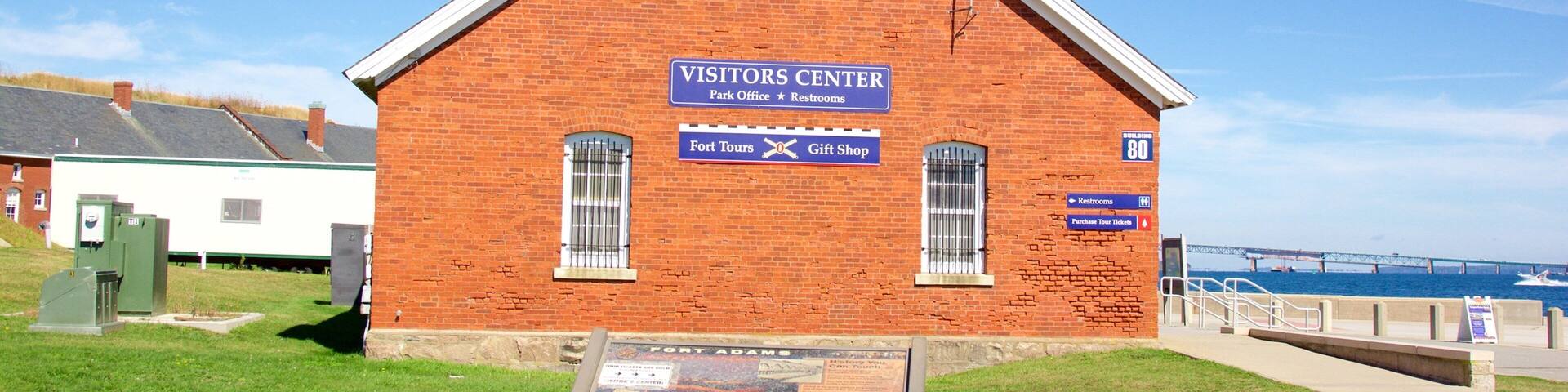 A brick building labeled "Visitors Center" with signs for "Fort Tours" and "Gift Shop."