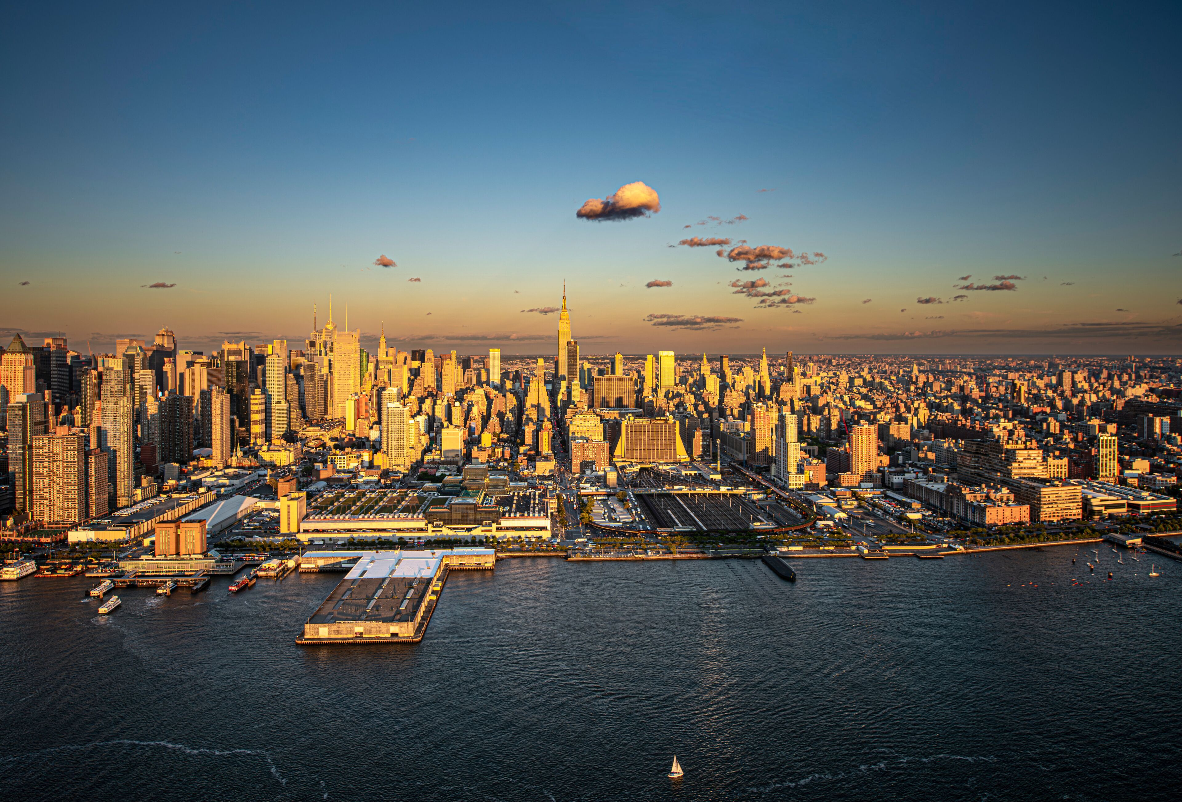 A city skyline with a prominent skyscraper, a large body of water, and a clear sky.
