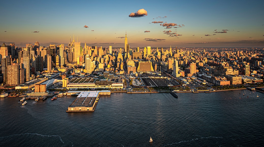A city skyline with a prominent skyscraper, a large body of water, and a clear sky.