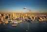 A city skyline with a prominent skyscraper, a large body of water, and a clear sky.
