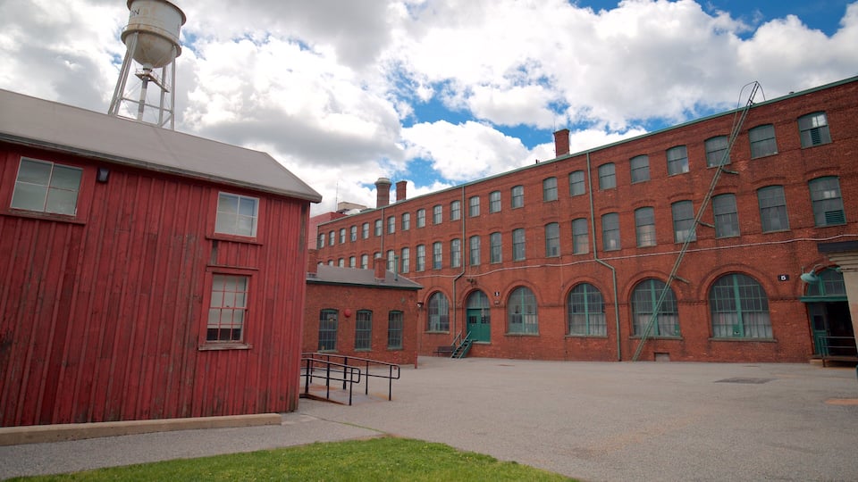 A red brick building with a water tower, a green staircase, and a grassy area.