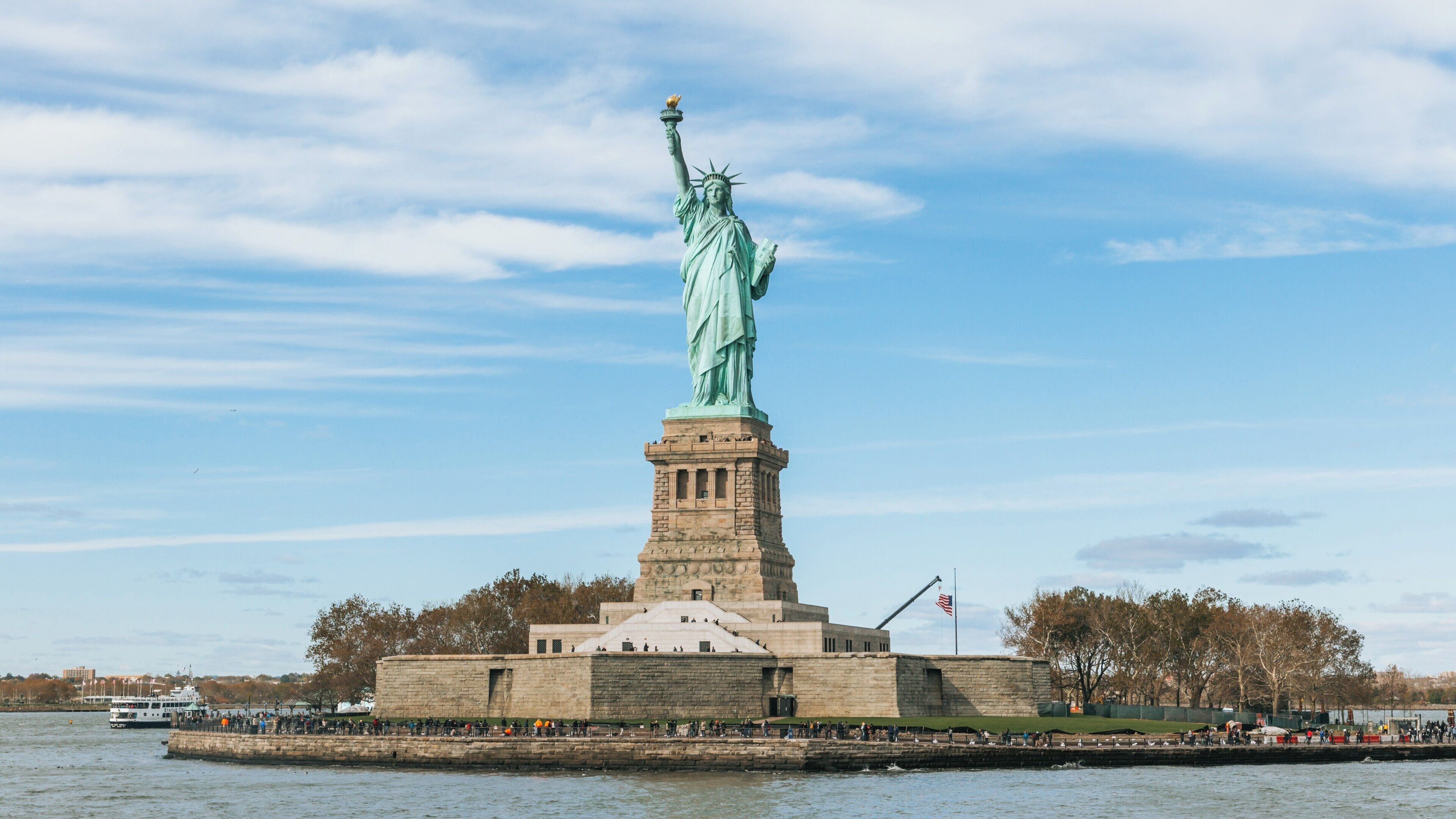 Iconic statue of liberty stands proudly in Manhattan, showcasing its grandeur against the skyline of New York City on a clear day