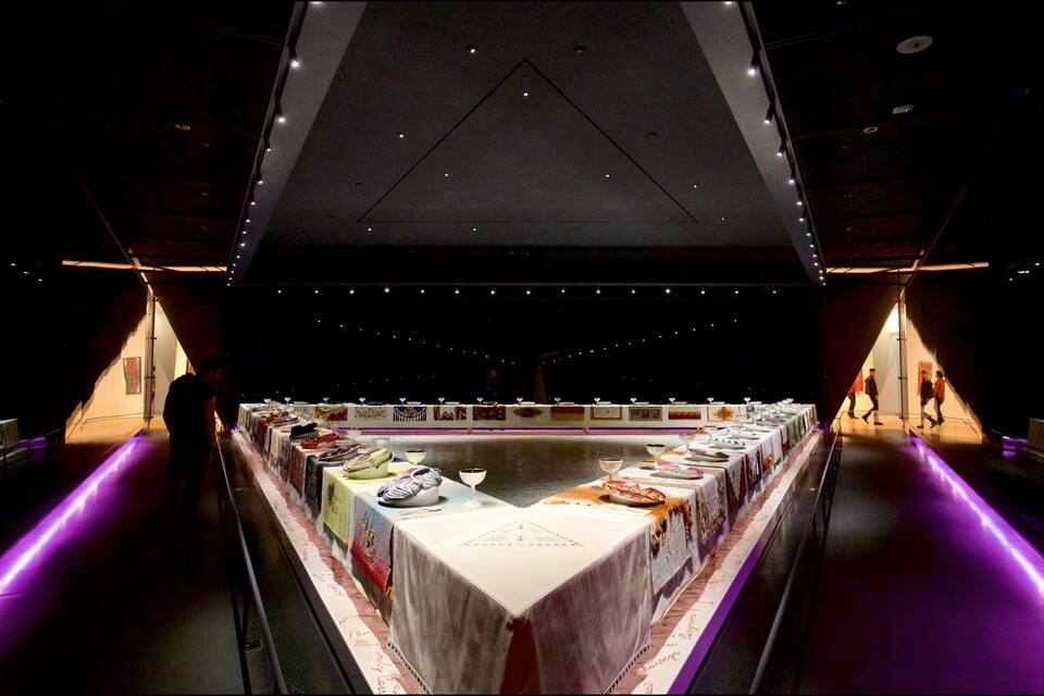 An art gallery with a long table displaying various artworks.