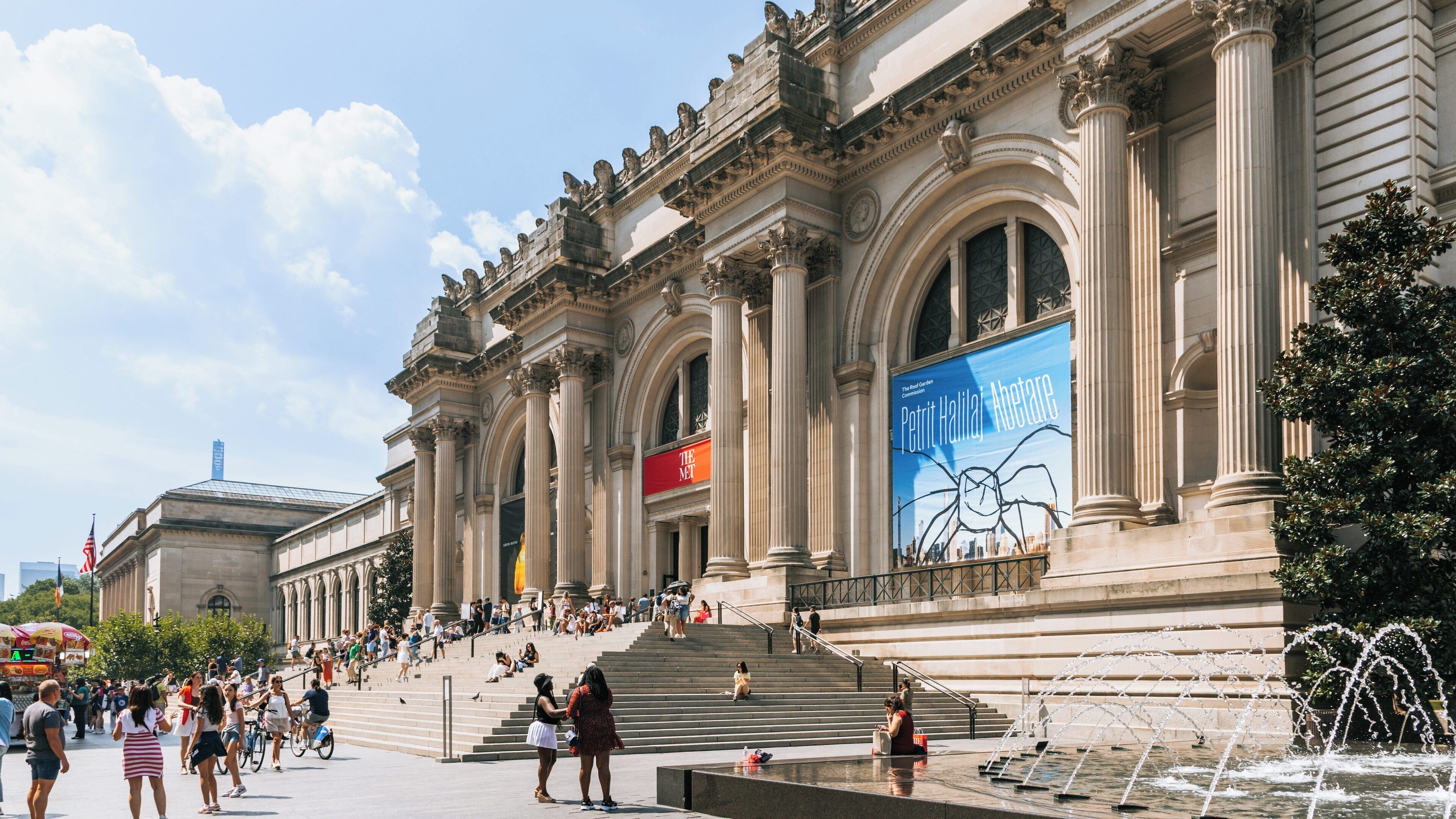 Visitors enjoying a sunny day at the Metropolitan Museum of Art in Manhattan, New York, surrounded by rich architecture and vibrant outdoor activity