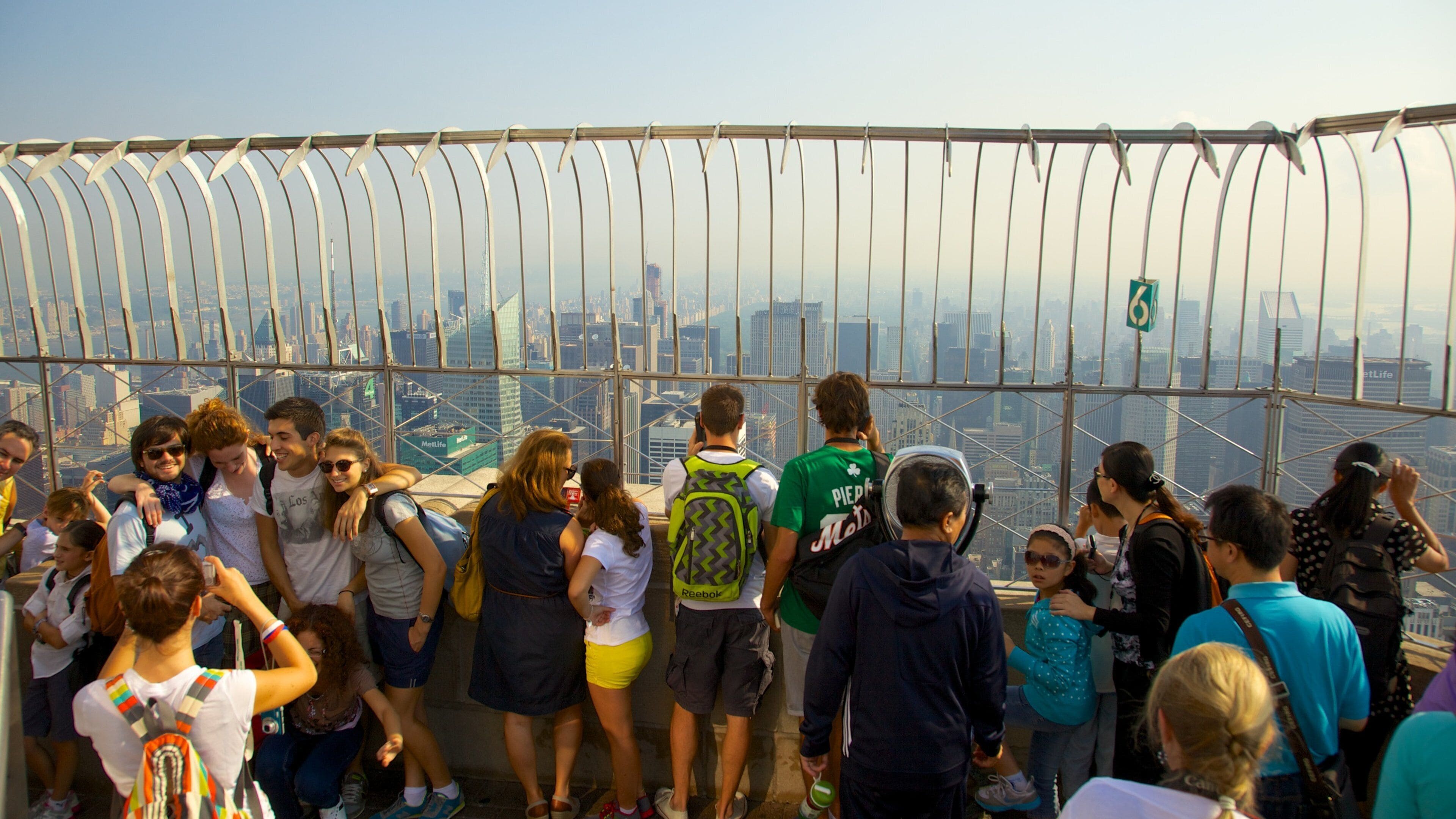 Crowds enjoying views from the observation deck of the Empire State Building in New York City on a sunny day