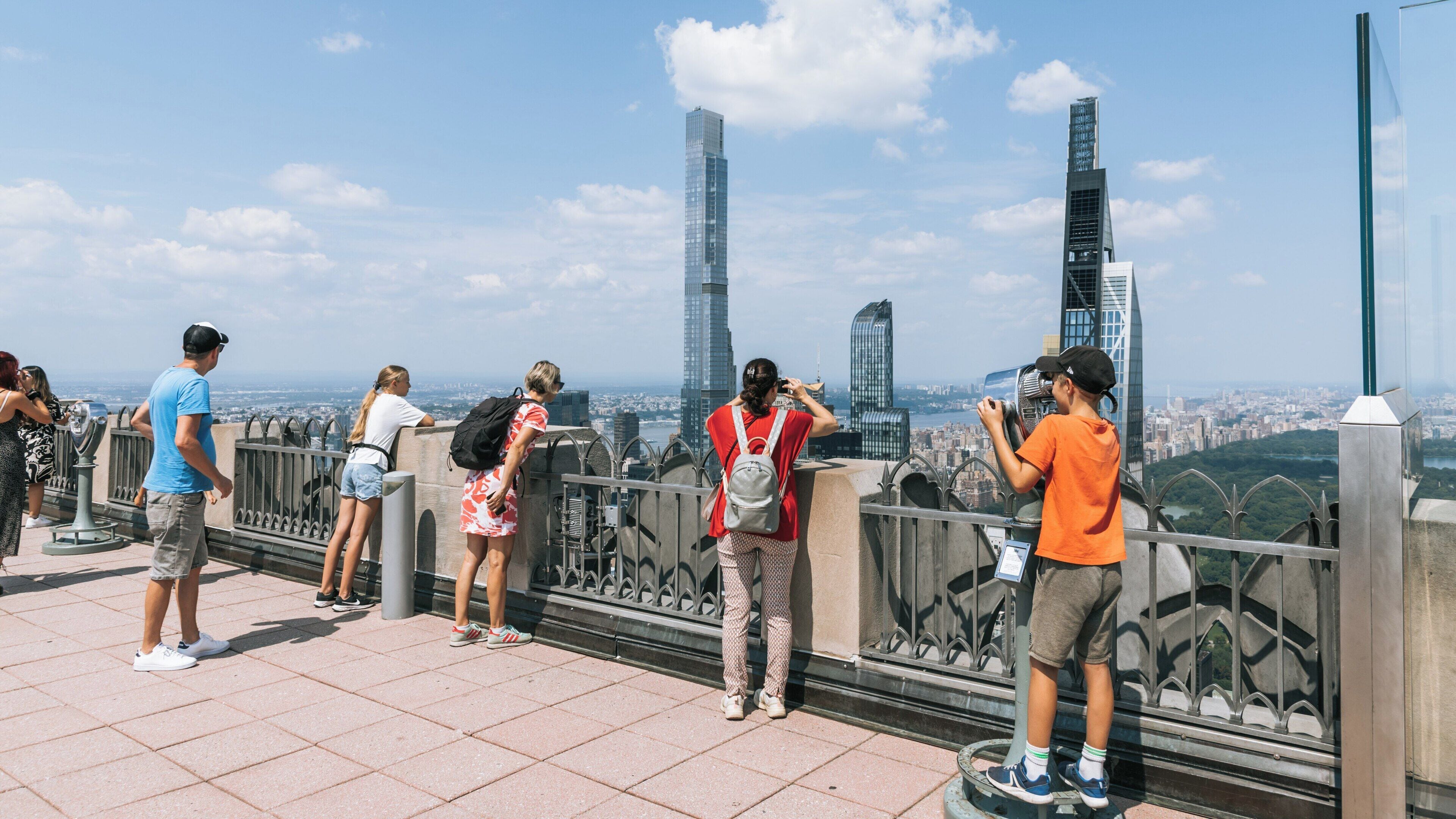 Visitors enjoy breathtaking views from the observation deck of Rockefeller Center in Manhattan, New York on a bright summer day