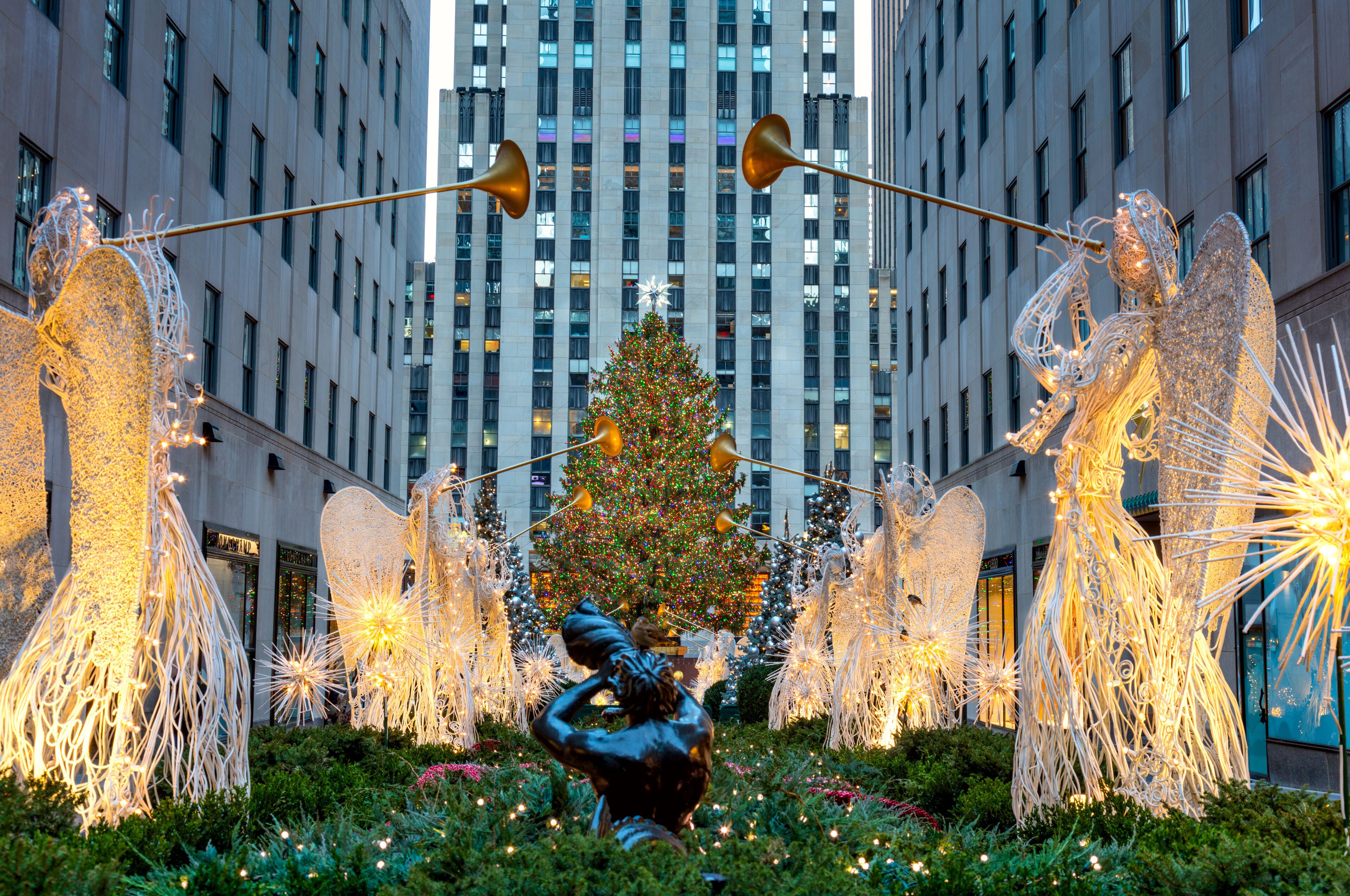 A Christmas tree, illuminated sculptures, and a statue in an urban setting.