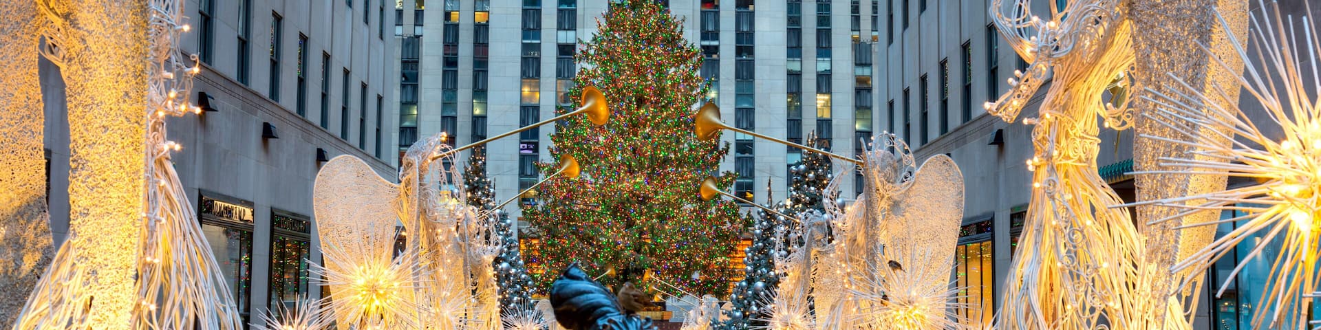 Un árbol de Navidad, esculturas iluminadas y una estatua en un entorno urbano.
