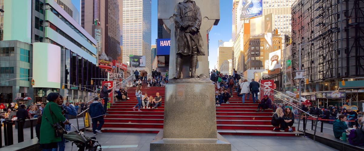 Times Square som visar en staty eller skulptur, ett höghus och affärsdistrikt