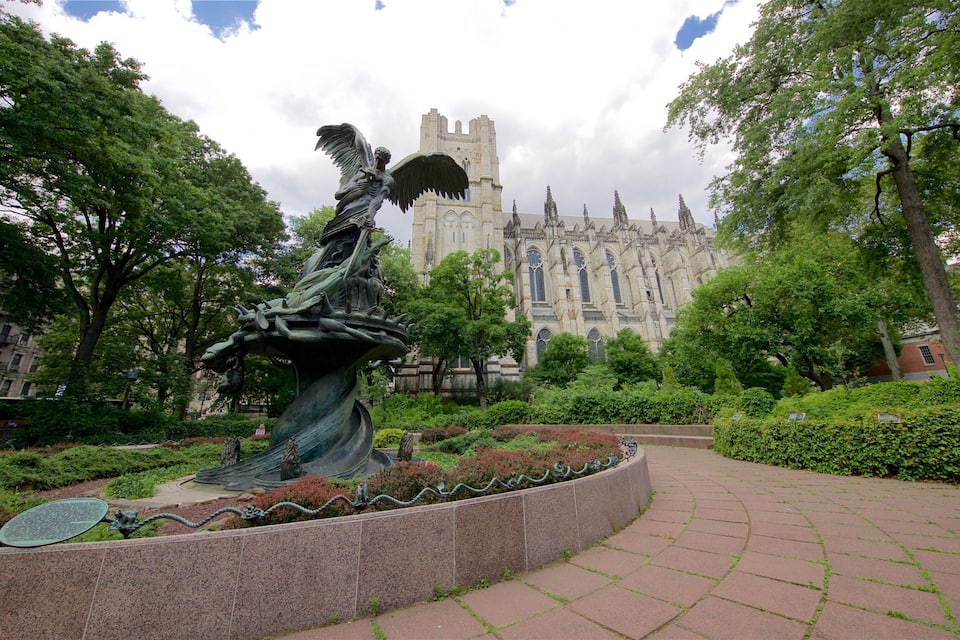 Estátua de uma mulher montada em um cavalo alado, num parque com uma grande catedral ao fundo.