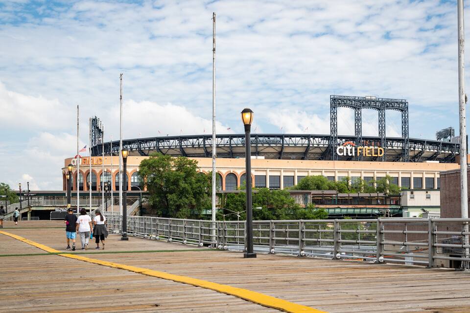 Un estadio de béisbol con un paseo marítimo de madera frente a él.
