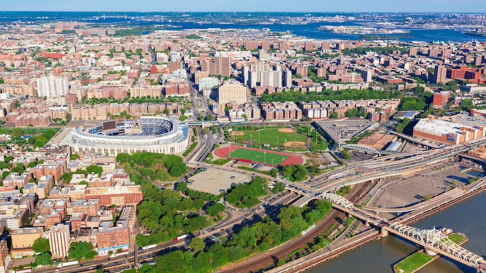 Eine Luftaufnahme einer Stadt mit einem markanten Stadion, einem Fluss und einer Brücke.