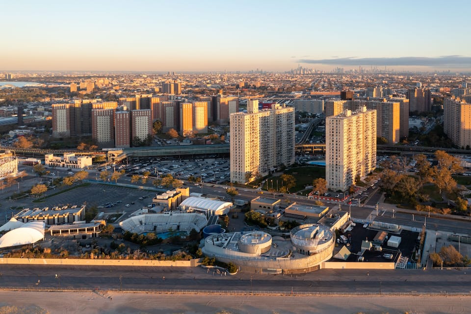 A cityscape with high-rise buildings, a stadium, and a bridge.