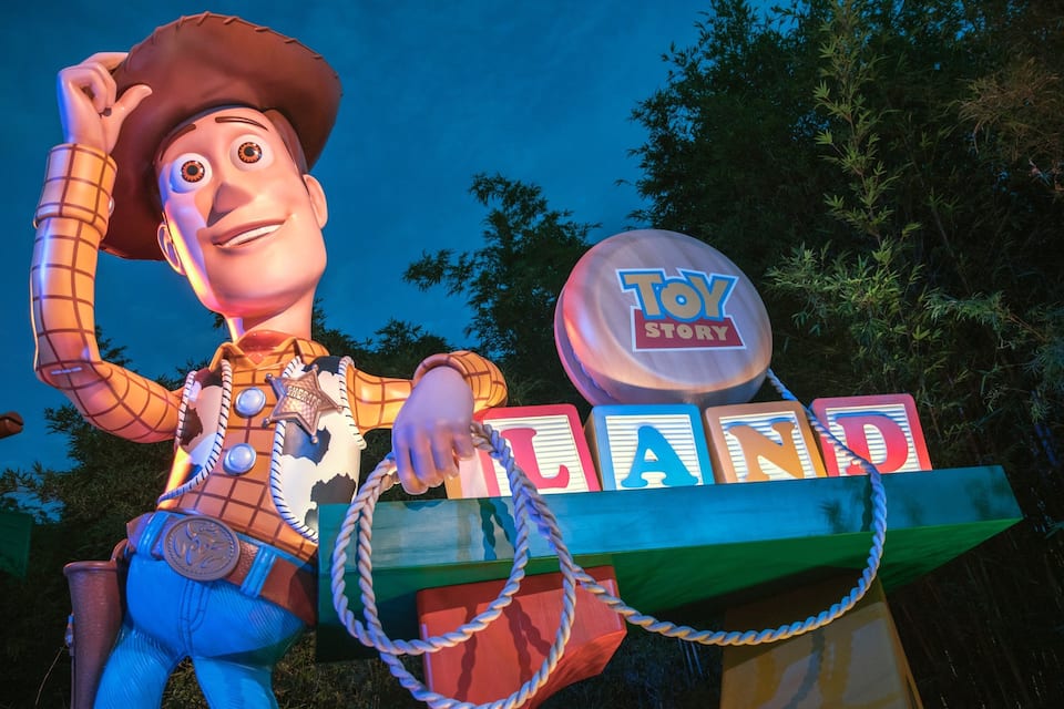Uma exposição temática de Toy Story, com uma figura de cowboy, uma placa 'Toy Story' e blocos coloridos formando a palavra 'LAND'.