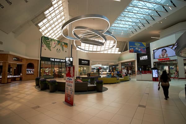 Um moderno centro comercial com teto alto, claraboias e uma área de estar central.