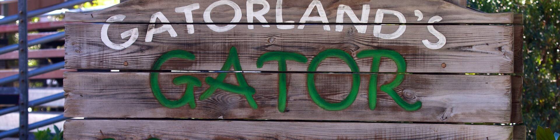 A wooden sign with "GATORLAND'S GATOR WRESTLING" and "ORLANDO FLORIDA" written on it.