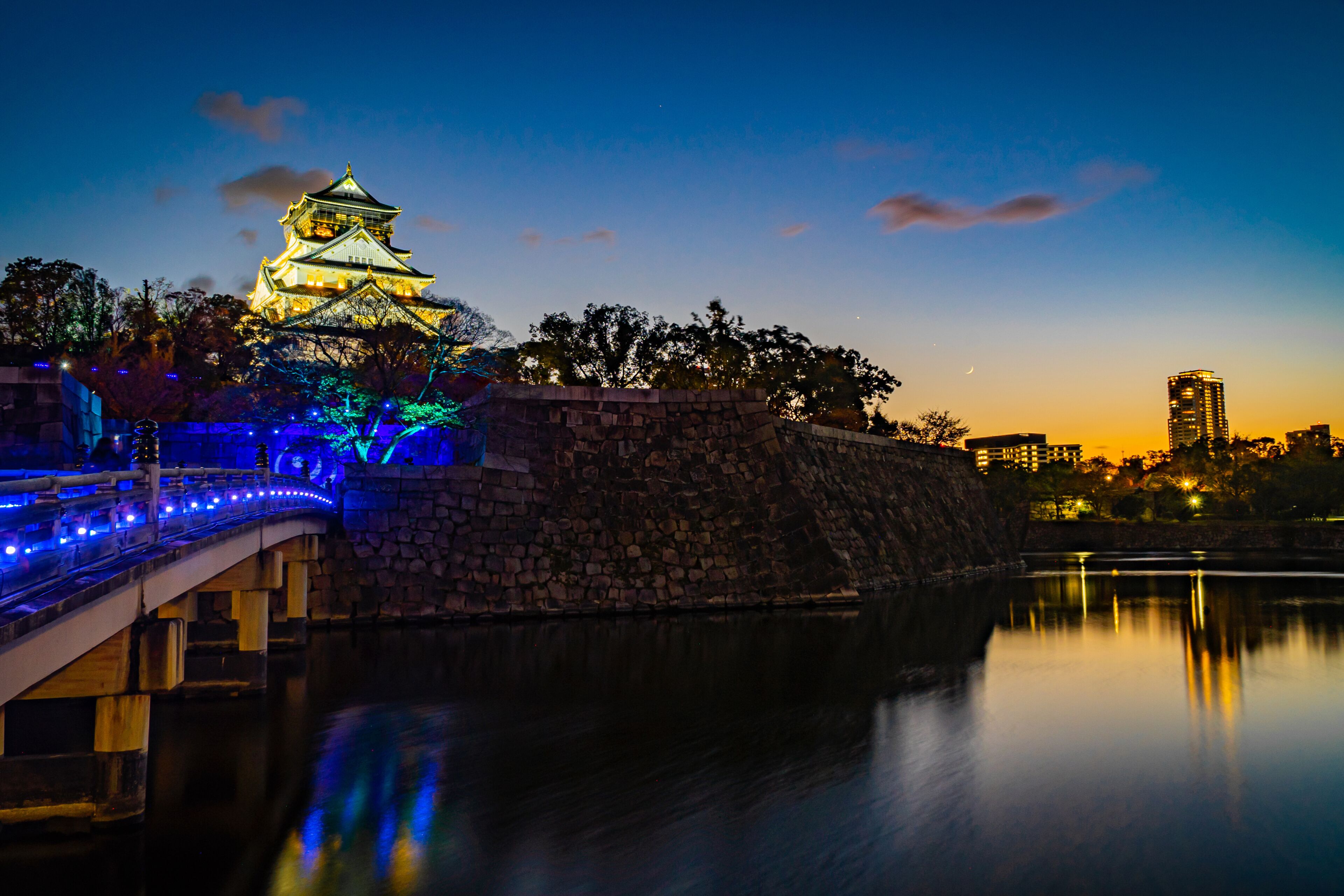 Osaka Castle or Himeji Castle at dusk decorated the light on the bridge in Christmas event contrast with modern Buildings in Osaka downtown.