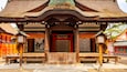 A traditional Japanese temple with a thatched roof, wooden beams, and a red entrance gate.
