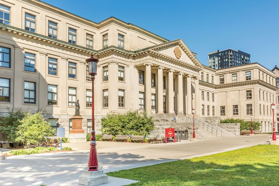 A historic building with classical architecture, a statue, and a well-maintained lawn.