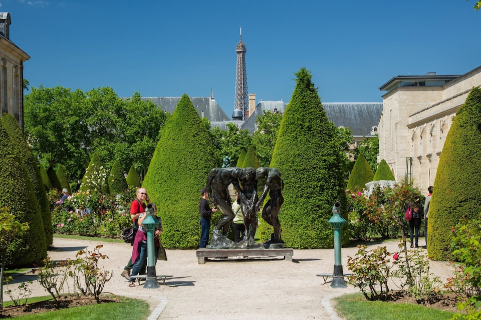 Ein Garten mit Formschnitten, einem Brunnen und dem Eiffelturm im Hintergrund.