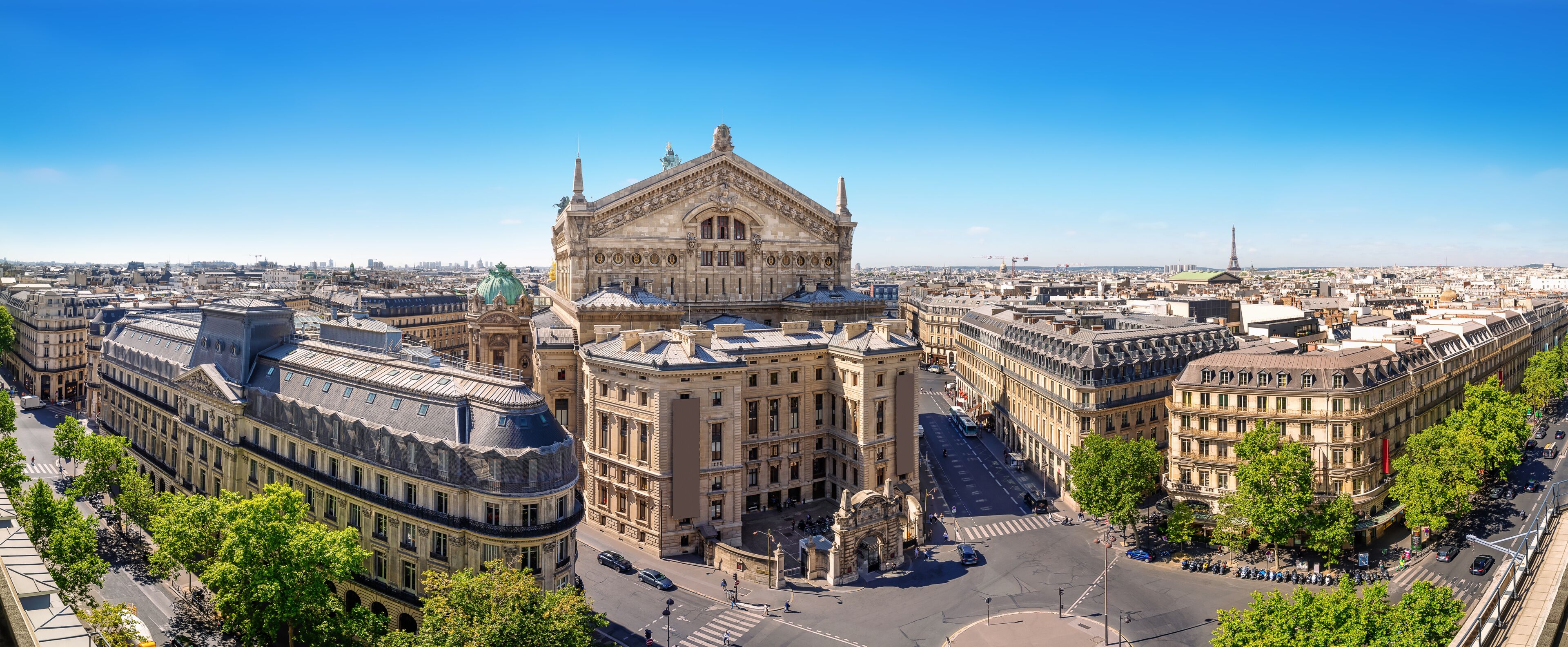 A historic building with ornate architecture, a large open square, and surrounding urban buildings.
