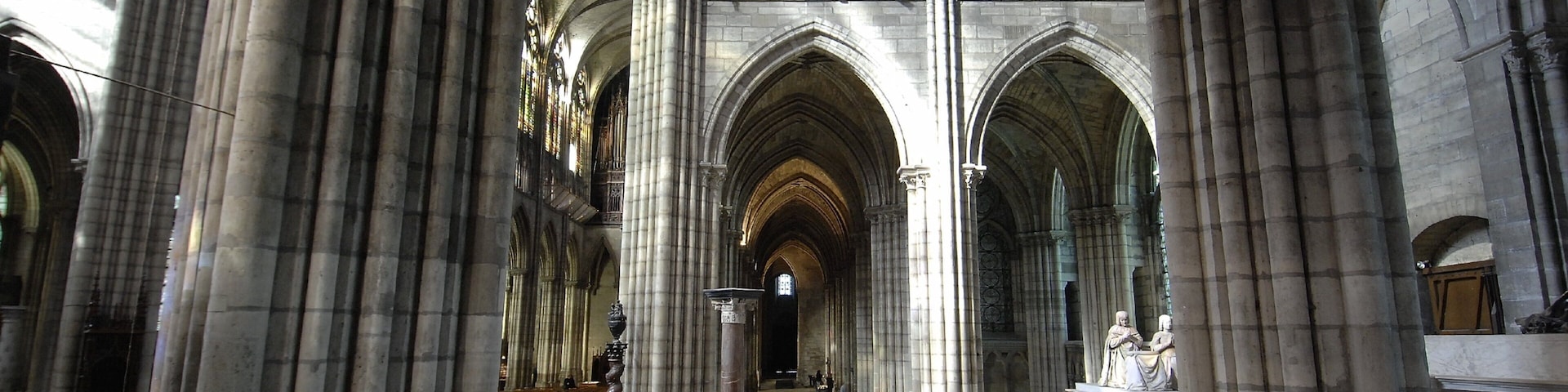A cathedral interior with high vaulted ceilings, large stained glass windows, and classical columns.