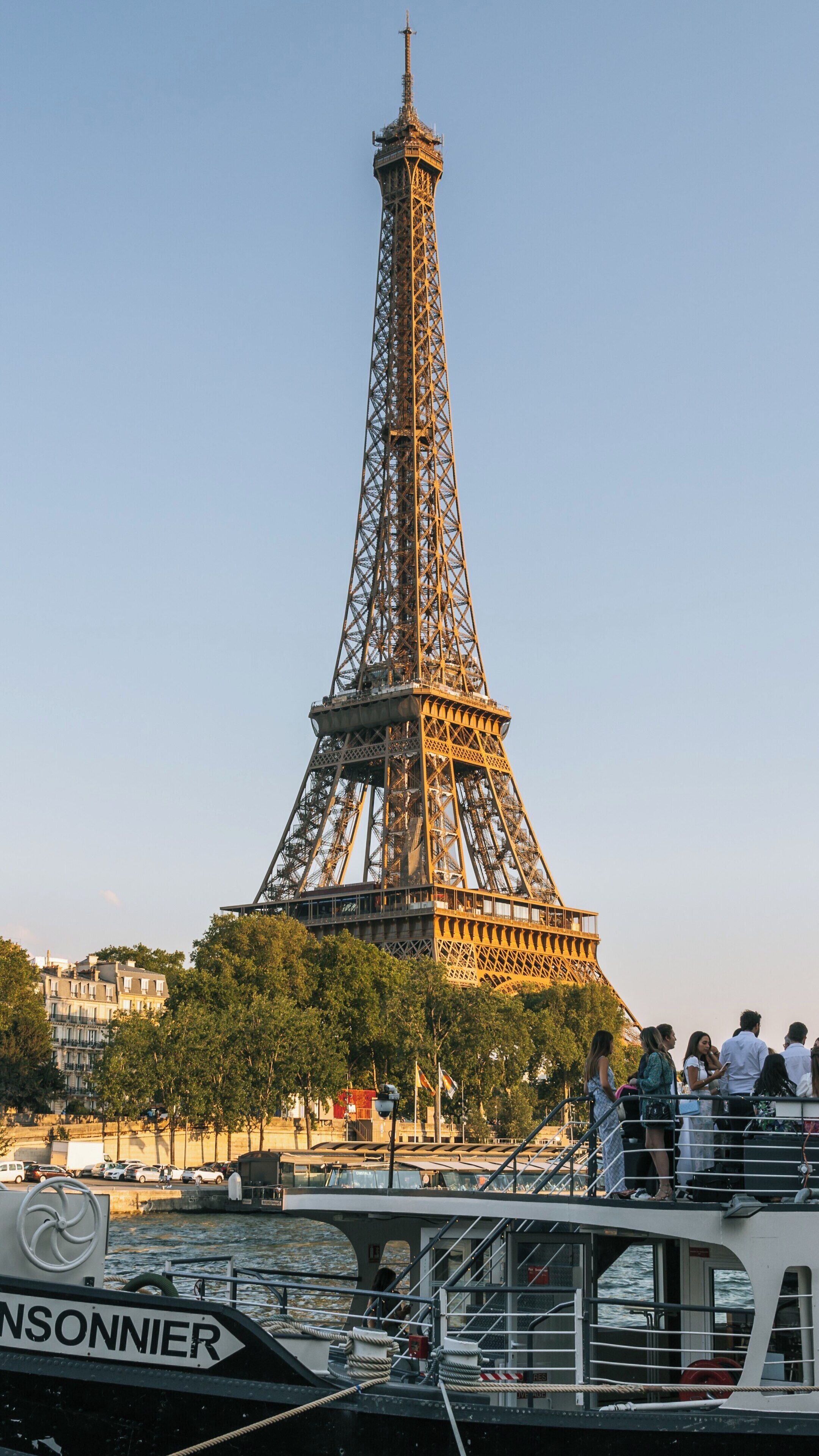 Golden hour at the Eiffel Tower in the 7th Arrondissement of Paris showcasing visitors enjoying the scenic view on a boat along the Seine River