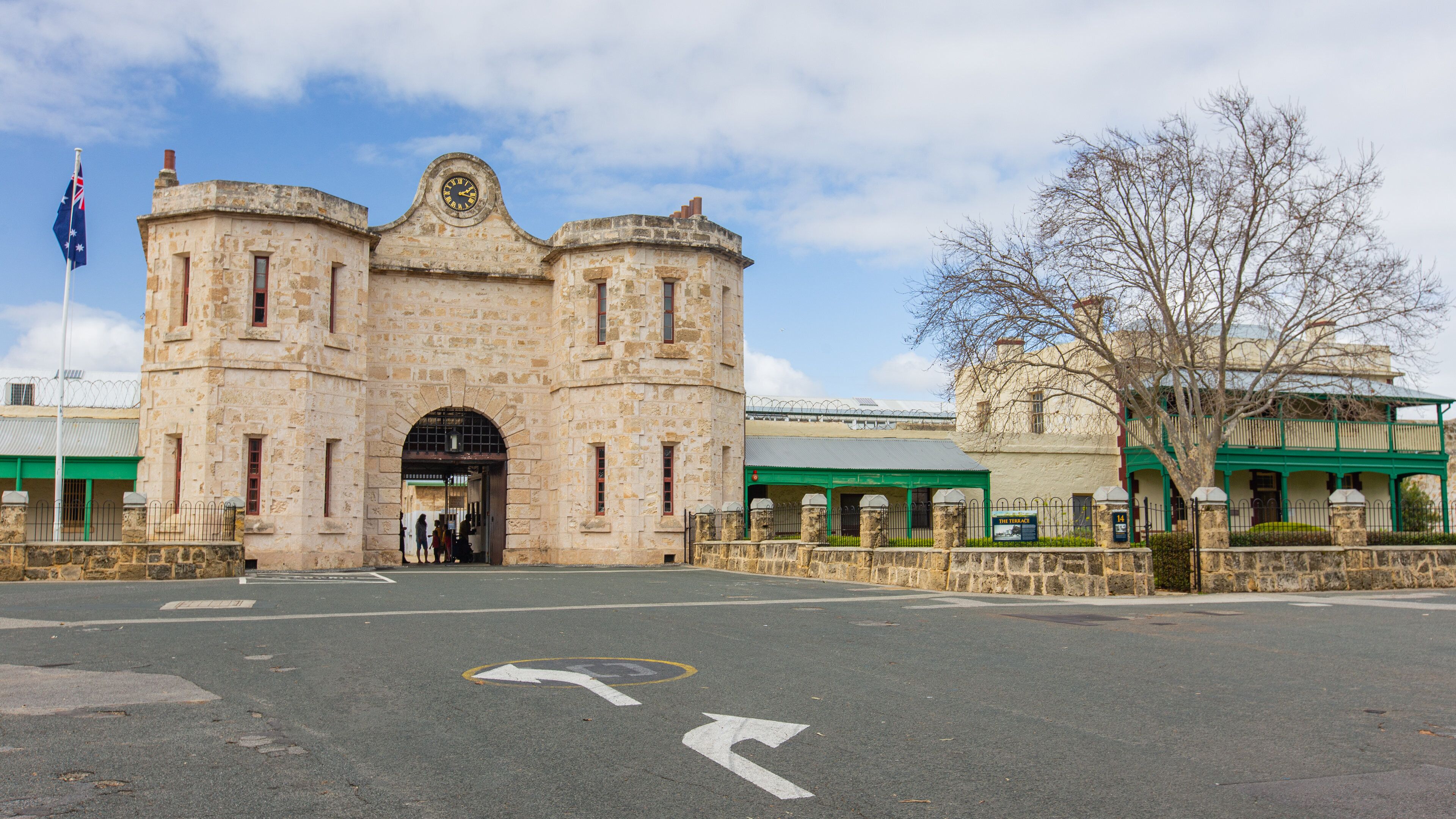 A historic stone building with a clock, a flag, and a sign reading "The Terrazzo".
