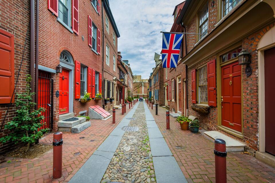 A brick-paved alley with red doors and a Union Jack flag.