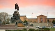 A statue of a man on horseback in front of a museum with classical architecture.