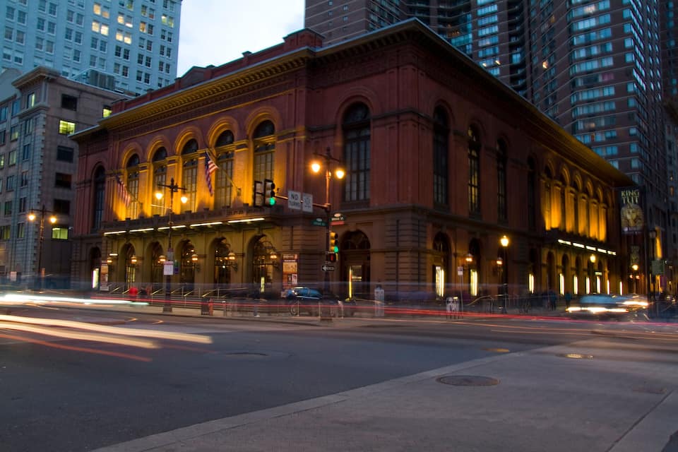 A historic building with arched windows and a red facade, located at a city intersection.