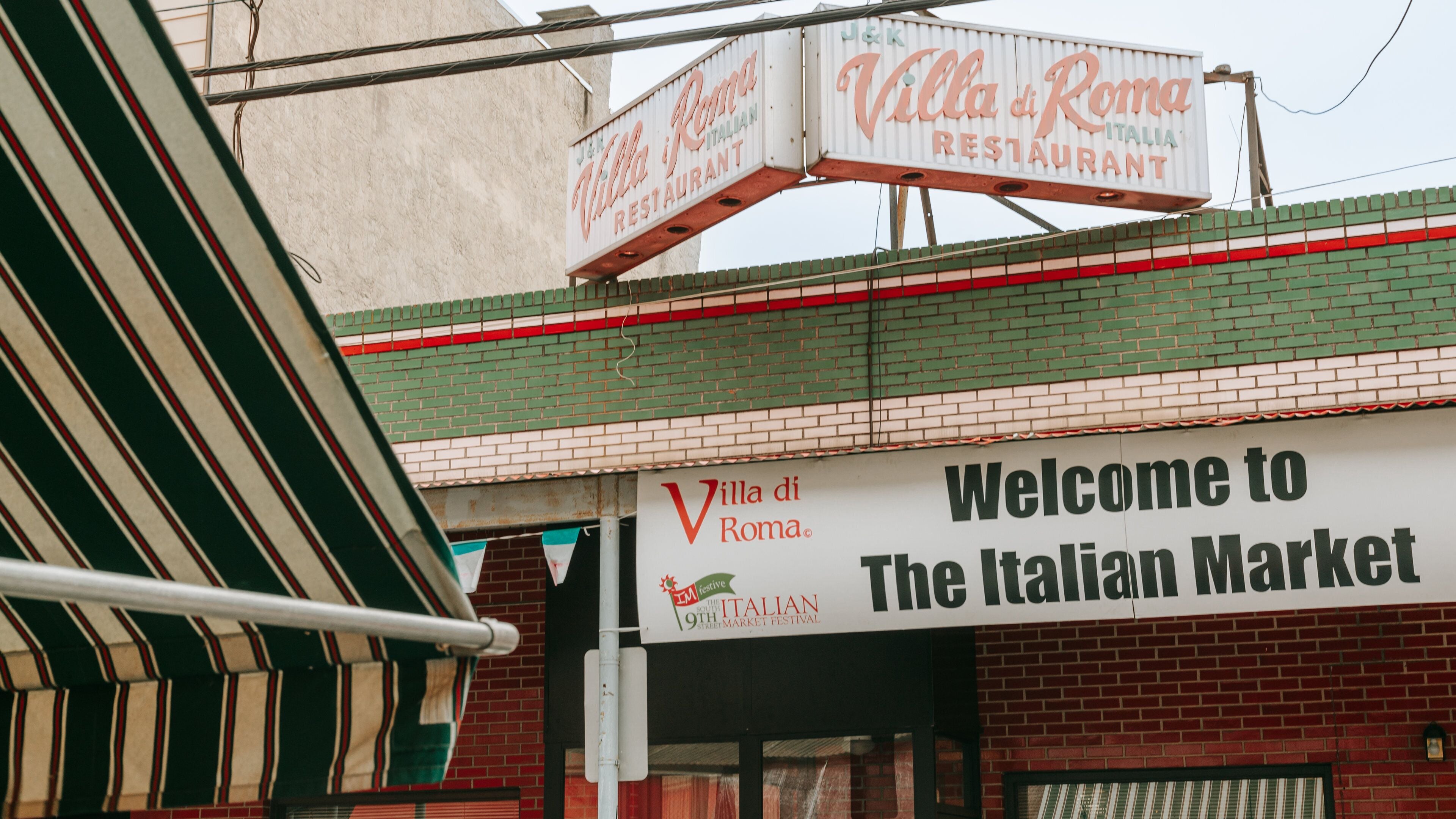 Schild für das italienische Restaurant Villa di Roma und ein Willkommensschild für The Italian Market.