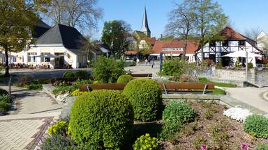 A town square with a church steeple, traditional half-timbered houses, and a café.