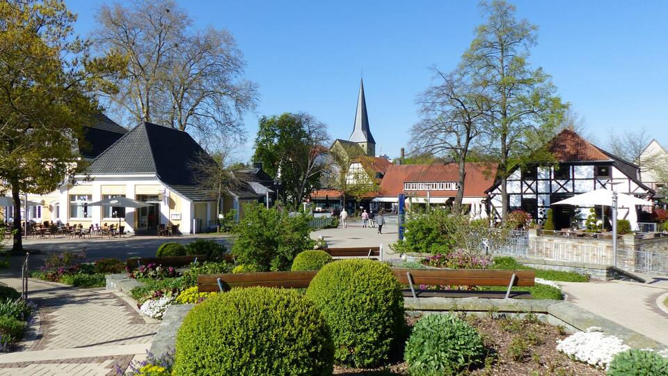 A town square with a church steeple, traditional half-timbered houses, and a café.