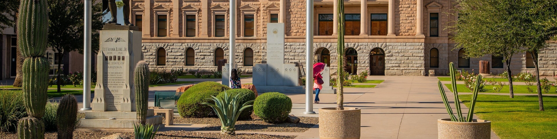 En bygning med en stenfacade, en statue og cactussen i forgrunden.