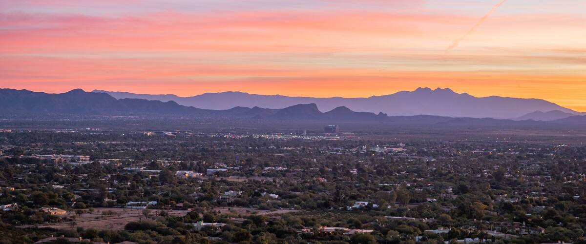 A cityscape at sunset with mountains in the background.
